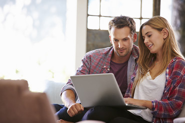 couple sitting on couch together looking at computer